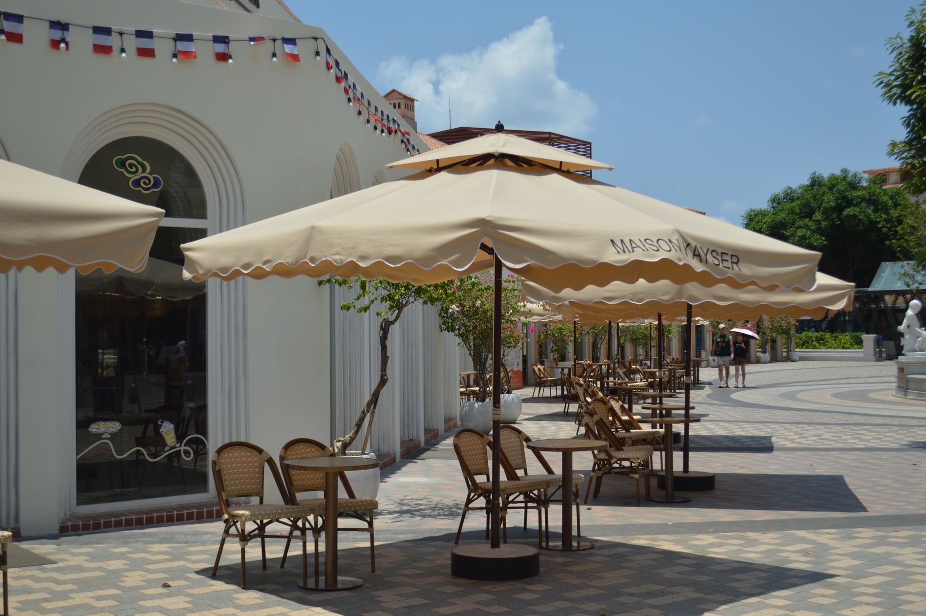 Sonnige Gastgarten-Terrasse mit Schirmen unter blauem Himmel